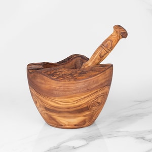 Handmade rustic mortar and pestle crafted from olive wood, ideal for grinding and mashing herbs and spices. Its robust construction and unique shape make it a valuable tool for any chef or home cook