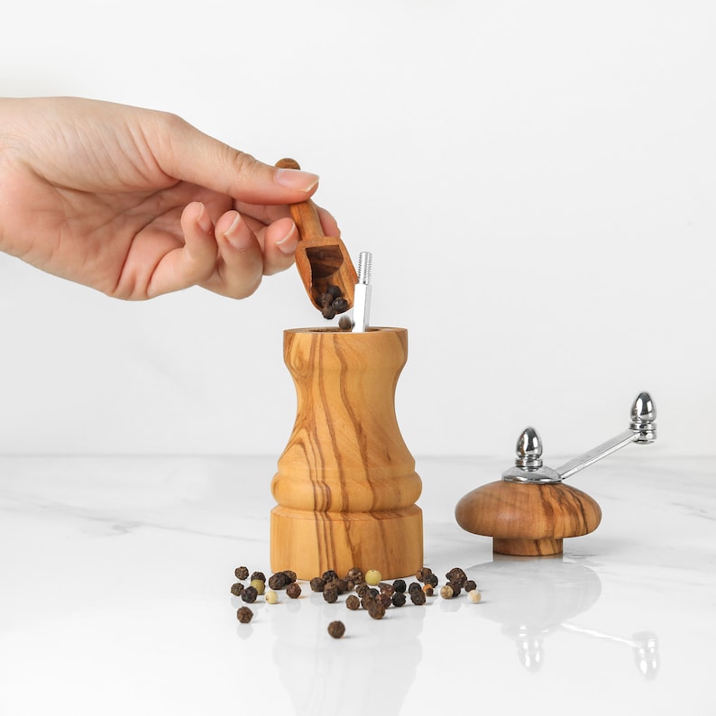 Artisanal Olive Wood Salt Grinder, with visible grain, durable for kitchen use, includes handle for easy grinding and free wood wax for care.