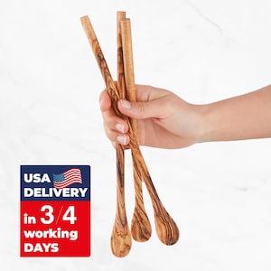 May include: Four olive wood spoons with a teardrop-shaped bowl and long, slender handles. The spoons are held in a hand against a white background. The wood grain is visible. The image also contains a USA delivery graphic.