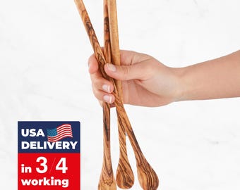 May include: Four olive wood spoons with a teardrop-shaped bowl and long, slender handles. The spoons are held in a hand against a white background. The wood grain is visible. The image also contains a USA delivery graphic.