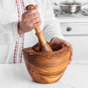 Rustic olive wood mortar and pestle, featuring a uniquely shaped bowl with natural edges and a matching pestle. Ideal for creating spice mixes and pastes while adding a touch of natural beauty to your kitchen.