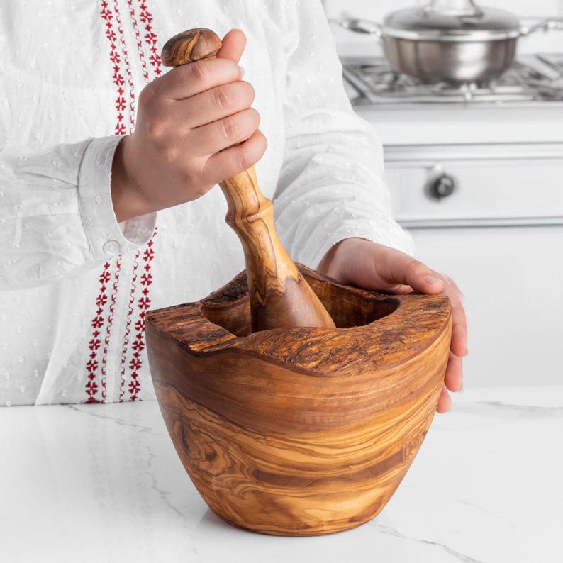 Rustic olive wood mortar and pestle, featuring a uniquely shaped bowl with natural edges and a matching pestle. Ideal for creating spice mixes and pastes while adding a touch of natural beauty to your kitchen.