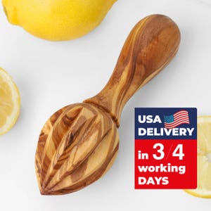 May include: A wooden citrus juicer with a grooved reamer and a long handle. The juicer is made of light and dark brown wood and is surrounded by lemons. The text "USA DELIVERY" is visible.