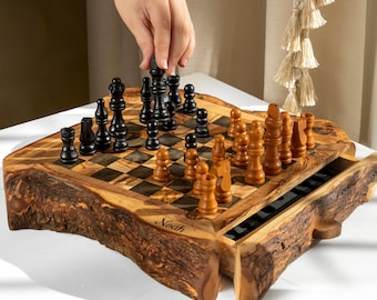 Puede incluir: Un juego de ajedrez de madera con borde natural de corteza y un cajón extraíble. El tablero tiene cuadrados de madera claros y oscuros, con piezas de ajedrez negras y marrones. El nombre Noah está grabado en la parte frontal.