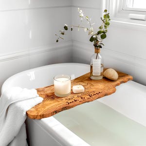 Elegant olive wood bath tray in a natural, irregular shape, designed to hold bath essentials securely over your bathtub. This unique wooden bath caddy is a must-have for a serene, spa-like experience at home.