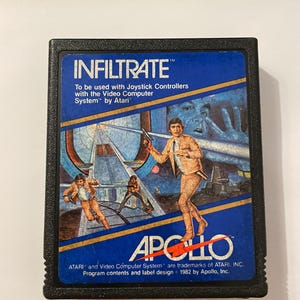 Könnte beinhalten: Eine Vintage Atari Videospiel-Cartridge für "INFILTRATE". Die Cartridge hat ein blaues Etikett mit Action-Artwork von Figuren in orangefarbenen Anzügen. Das "APOLLO"-Logo ist prominent dargestellt. Text enthält "To be used with Joystick Controllers with the Video Computer System by Atari."