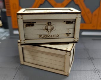 May include: Two wooden crates stacked on top of each other. The top crate has a Cobra logo and the text "PLASMATOX" printed on the front.