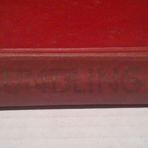 May include: A vintage hardcover book with a red cover. The title "THE ROARING" is embossed on the spine, along with the author's name, Francis Cardinal Spellman, and the publisher's name, Scribners.