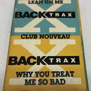 May include: A vintage music cassette tape case with a teal and yellow design. The text "LEAN ON ME", "BACK TRAX", "CLUB NOUVEAU", and "WHY YOU TREAT ME SO BAD" are visible on the cover.