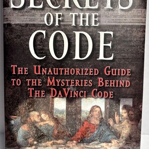 May include: Book cover with a white title "Secrets of the Code" and subtitle "The Unauthorized Guide to the Mysteries Behind The DaVinci Code". The cover features a painting of the Last Supper with a red background.