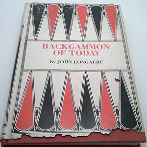 May include: A vintage book titled "Backgammon of Today" by John Longacre. The cover features a black and white design with red triangles.