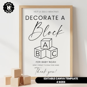 Może przedstawiać: Oprawiony znak z napisem "Udekoruj blok" i "Dla dziecka Noah". Znak zawiera grafikę bloków ABC. Znak znajduje się w jasnej drewnianej ramie. Przed znakiem znajdują się drewniane klocki.