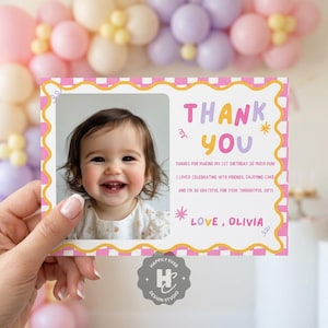 May include: A thank you card with a photo of a smiling baby. The card has a pink and yellow border and reads "Thank You" in colorful letters. The text also includes a message of gratitude and the name "Olivia".