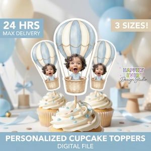 May include: Cupcakes topped with personalized hot air balloon toppers featuring a baby's face. The toppers are blue and white, with the text "24 HRS MAX DELIVERY" and "3 SIZES!" visible. The cupcakes have white frosting with blue and tan sprinkles.
