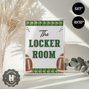 May include: Clear acrylic sign with the text "The Locker Room" in black and green. The sign features football graphics and a field design border. Available in 5x7 inch and 8x10 inch sizes.