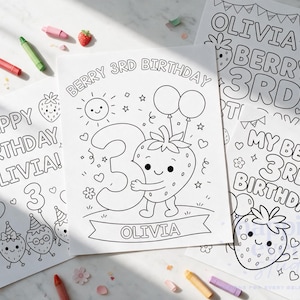 May include: Three white paper coloring sheets featuring black line art for a third birthday. Designs include a smiling strawberry character, the number 3, balloons, and the text "Berry 3rd Birthday" and "Olivia". Scattered crayons surround the pages.