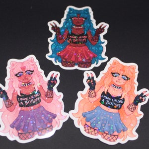 May include: Three holographic stickers featuring a cartoon character with pink, blue, and orange hair. The character is wearing a black crop top with the text "I MADE UR DAD A BOTTOM" and a short skirt with a star pattern. The character is making a peace sign with both hands.