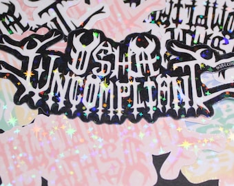 May include: A collection of holographic stickers with various designs, including the words "We Shall Be Uncompliant" in a gothic font with stars and a black background.