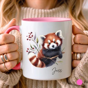 Puede incluir: Taza de cer&aacute;mica blanca con borde rosa, con una ilustraci&oacute;n de acuarela de un panda rojo con una rama frondosa. La taza tiene el nombre "Jess" escrito en cursiva en la parte inferior.