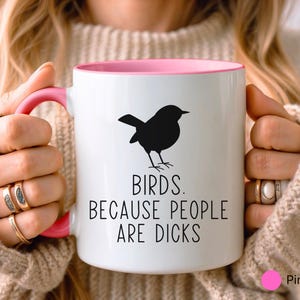 Pode incluir: Caneca de cer&acirc;mica branca com interior e al&ccedil;a rosa. Uma silhueta preta de um p&aacute;ssaro &eacute; impressa na frente, com o texto "BIRDS. BECAUSE PEOPLE ARE DICKS."