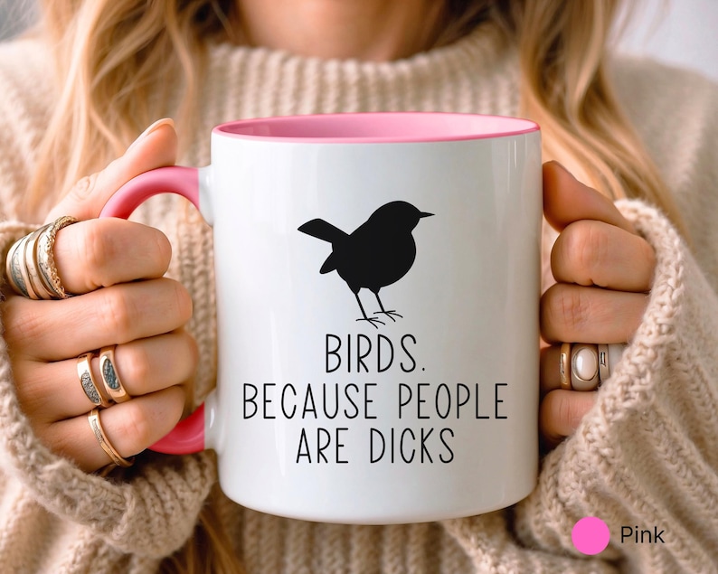 Pode incluir: Caneca de cer&acirc;mica branca com interior e al&ccedil;a rosa. Uma silhueta preta de um p&aacute;ssaro &eacute; impressa na frente, com o texto "BIRDS. BECAUSE PEOPLE ARE DICKS."