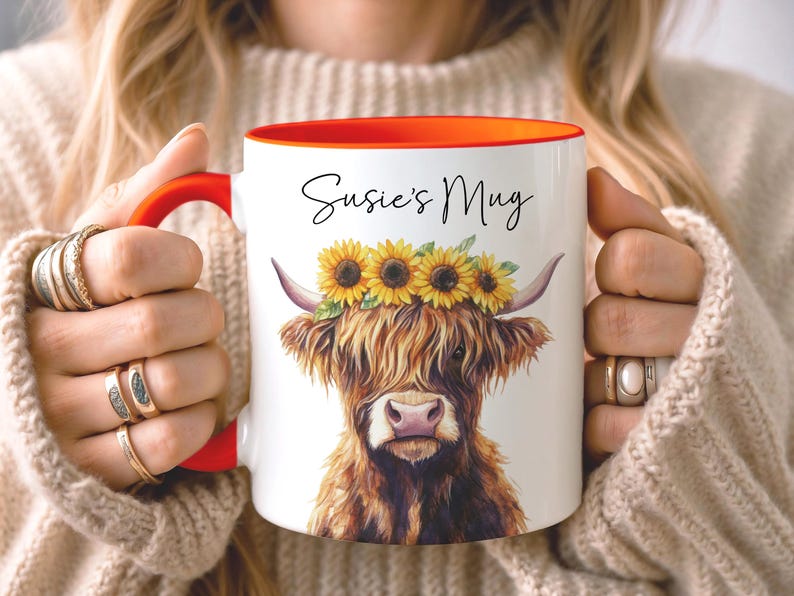 May include: White ceramic mug with a red handle and interior. The mug features a watercolor illustration of a Highland cow wearing a sunflower crown, with the text "Susie's Mug" in black script.