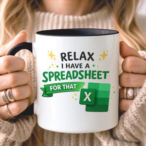 Könnte beinhalten: Ein weißer Keramikbecher mit schwarzem Henkel und Rand, bedruckt mit dem Text RELAX I HAVE A SPREADSHEET FOR THAT in schwarzer und grüner Schrift. Das Design enthält eine grüne Banderole und ein grünes quadratisches Symbol mit einem weißen X.