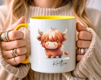 May include: White ceramic mug with a yellow interior and handle. The mug features a watercolor illustration of a Highland cow with brown and white fur. The name "Kaitlin" is written in cursive below the cow.