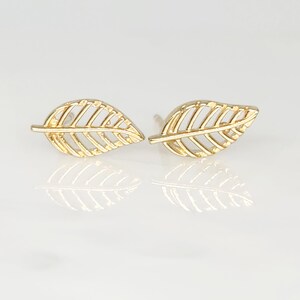May include: A pair of gold leaf stud earrings. The earrings are made of a delicate, openwork design.
