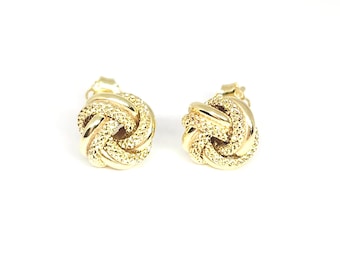 May include: A pair of gold stud earrings featuring a spherical knot design. Each earring is crafted with a combination of polished gold bands and textured, diamond-cut gold surfaces that create a shimmering, multi-dimensional appearance.