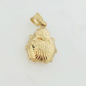 K&ouml;nnte beinhalten: Ein goldener Anh&auml;nger in Form eines Marienk&auml;fers mit polierter Oberfl&auml;che. Das Insektendesign zeigt gepr&auml;gte kreisf&ouml;rmige Muster auf den Fl&uuml;geln und einen glatten Kopfbereich. Eine kleine dreieckige &Ouml;se ist oben zur Befestigung angebracht.