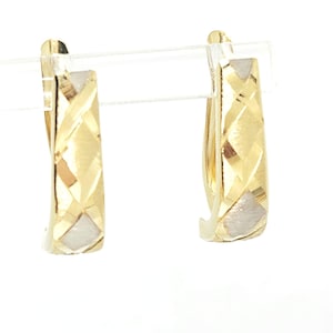 May include: A pair of gold hoop earrings featuring a textured, diamond-cut lattice pattern across the front surface. The earrings have a polished finish with alternating matte and shiny sections, creating a geometric design on the curved metal.