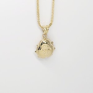 K&ouml;nnte beinhalten: Eine goldene Halskette mit einem polierten goldenen Anh&auml;nger in Form eines Marienk&auml;fers. Der Anh&auml;nger h&auml;ngt an einer goldenen Weizenkette. Das Marienk&auml;fer-Design umfasst gravierte Details auf den Fl&uuml;geln und einen glatten, abgerundeten Kopf, alles in einem hellen, reflektierenden Gold-Finish.