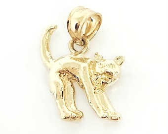 May include: A polished gold pendant shaped like a cat with an arched back and a raised tail. The cat is depicted in a standing position with its head turned slightly to the side. A small, rounded gold bail is attached to the top for hanging.