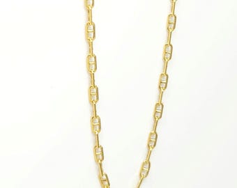 May include: A gold-toned chain necklace featuring elongated oval links, each bisected by a central horizontal bar. The chain is composed of uniform, repeating links that create a structured, linear design with a polished, reflective metallic finish.