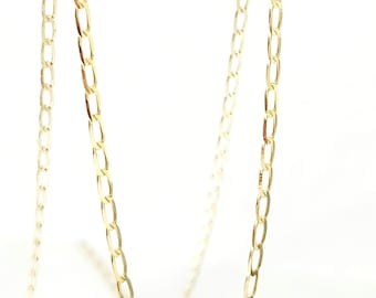 Puede incluir: Un collar de cadena en tono dorado con eslabones ovalados alargados conectados en una serie continua. La cadena tiene una superficie pulida y reflectante, y cuelga en una curva suave, mostrando el tamaño y la forma uniforme de cada eslabón.