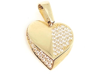 May include: A gold heart-shaped pendant featuring a smooth polished surface on one side and a pavé-set section of clear white stones on the other. The pendant includes a gold bail at the top for attachment to a chain or necklace.