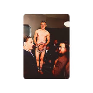 May include: A group of men in a room, one man is standing shirtless holding a hat in front of him. The men are all wearing suits and ties.