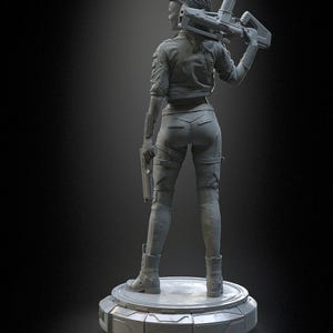 Pode incluir: Uma estatueta monocrom&aacute;tica cinza de um personagem em p&eacute; sobre uma base circular. O personagem veste uma jaqueta, cal&ccedil;as justas e botas, segurando um rifle sobre um ombro e uma pistola na outra m&atilde;o. O texto PATREON h3LLcreator &eacute; vis&iacute;vel.