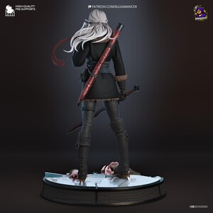 May include: A figurine of a character with long white hair, wearing a black coat with fur trim, dark pants, and boots. The character carries a long sword with a red scabbard on their back and stands on a circular base with a figure underneath.