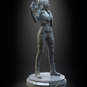 Pode incluir: Uma figura de resina cinza de um personagem com penteado moicano, vestindo uma jaqueta curta, cal&ccedil;as t&aacute;ticas e botas com fivelas. O personagem segura um rifle futurista e est&aacute; em uma base circular com o texto PATREON h3LLcreator.