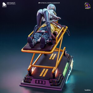 May include: A detailed figurine depicting a futuristic scene. A figure in a white jacket and black leggings leans over a person strapped to a yellow stretcher. The stretcher is on a platform with neon accents. The base is purple and black.
