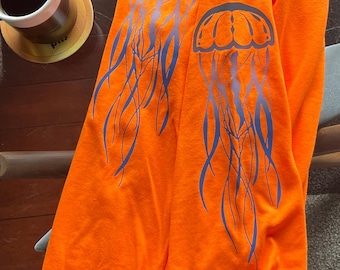 May include: Orange long-sleeved shirt with a blue jellyfish graphic on each sleeve.