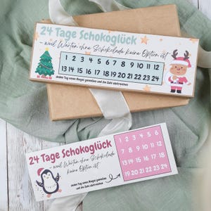 Puede incluir: Dos calendarios de adviento rectangulares con el texto "24 días de felicidad con chocolate" en alemán. Uno presenta un árbol de Navidad y un reno con traje de Papá Noel, el otro un pingüino. Cada calendario tiene los números 1-24.