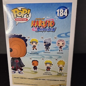 Pu&ograve; includere: Una scatola Funko Pop! Animation con personaggi di Naruto Shippuden. La scatola mostra immagini di Naruto, Kakashi, Sakura e Tobi. Il testo include "COLLEZIONALI TUTTI!" e il logo Funko. La scatola &egrave; numerata 184.