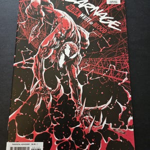 May include: A comic book cover featuring the character Carnage in a dynamic pose. The artwork is primarily black, white, and red, with the title "Carnage Black White & Blood" prominently displayed. The Marvel logo and issue number are visible.