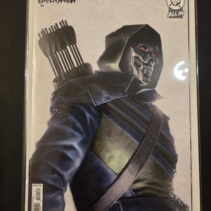 May include: A comic book titled Absolute Green Arrow #1 featuring a character in a dark hooded jacket and a skull mask with red eyes. The character carries a quiver of arrows on their back. The cover includes the DC logo and the text ALL IN.