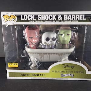 Pode incluir: Um conjunto em caixa de figuras de vinil com Lock, Shock e Barrel de "O Estranho Mundo de Jack". As figuras estão numa banheira branca, com o texto "MOVIE MOMENTS" e "25 YEARS". A caixa tem o logótipo "POP!".