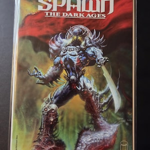 Puede incluir: Portada de cómic de "Spawn: The Dark Ages" con una figura musculosa y blindada con una espada. La figura es predominantemente azul y gris, sobre un fondo rojo y verde. El título "Spawn" se muestra prominentemente en la parte superior.