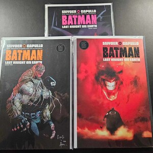 May include: Three comic book covers for Batman: Last Knight on Earth. The covers feature a red and black colour scheme with a dark, gritty style. The first cover features a close-up of Bane's face, the second cover features a close-up of the Joker's face, and the third cover features Batman standing in front of a red background.